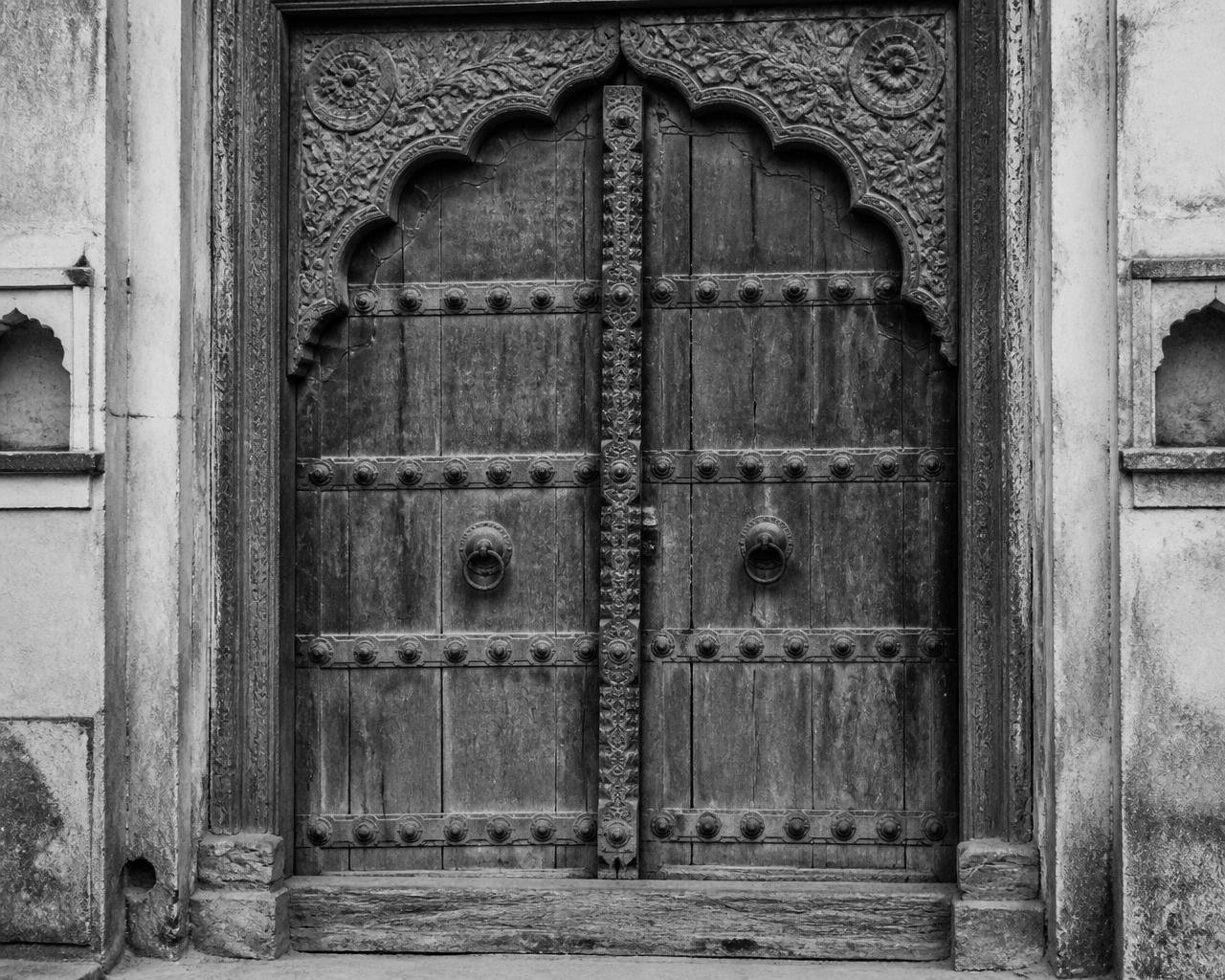 Carved wooden haveli door with iron studs